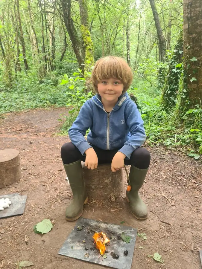 A young child enjoying a Forest School experience in the woodland